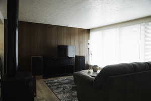 Living room with wood walls, a Napolean gas stove, light LVP floors, and a textured ceiling
