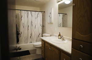 Bathroom with vanity, a textured ceiling, shower / bath combination with curtain, and LVP flooring.
