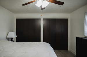 Bedroom featuring two closets, LVP flooring, a textured ceiling, and ceiling fan