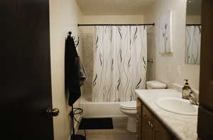 Full bath featuring a textured ceiling, vanity, shower / bath combination with curtain, and LVP flooring