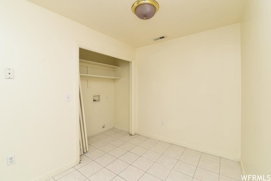 Laundry area with light tile patterned floors and baseboards