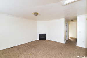 Carpeted empty room with crown molding and a fireplace