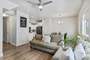 Living room with ceiling fan, suspended lighting, and light wood finished floors