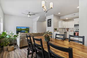 Dining space with light wood-style floors, a ceiling fan, and a chandelier