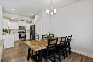 Dining area with dark wood-style flooring and suspended lighting