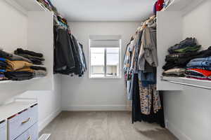 Walk in closet featuring light colored carpet
