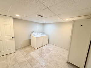 Laundry area with a drop ceiling, separate washer and dryer, and recessed lighting