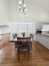 Dining room with dark wood finished floors, vaulted ceiling, and a chandelier