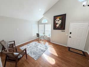 Living area featuring wood finished floors, vaulted ceiling, an office area, and recessed lighting