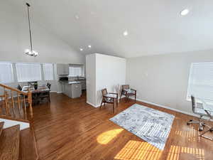 Office area with dark wood-style flooring, vaulted ceiling, and hanging lights