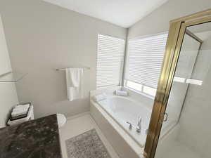 Bathroom with a shower stall, a garden tub, vaulted ceiling, and tile patterned flooring
