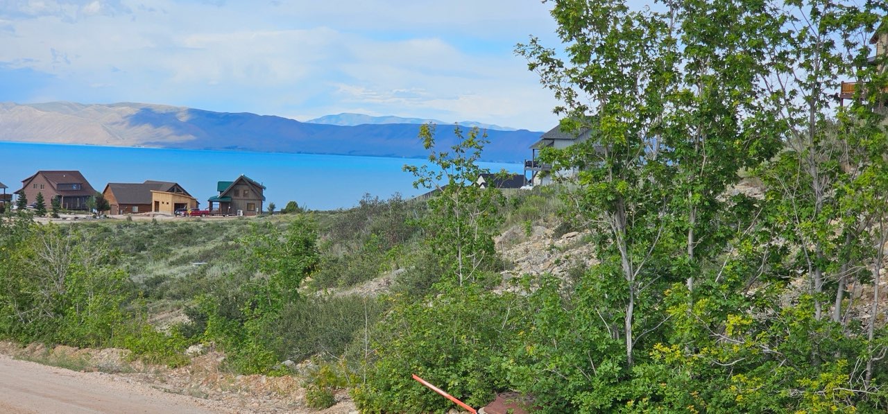 Sloping hillside property with existing residential structures and a prominent lake backdrop