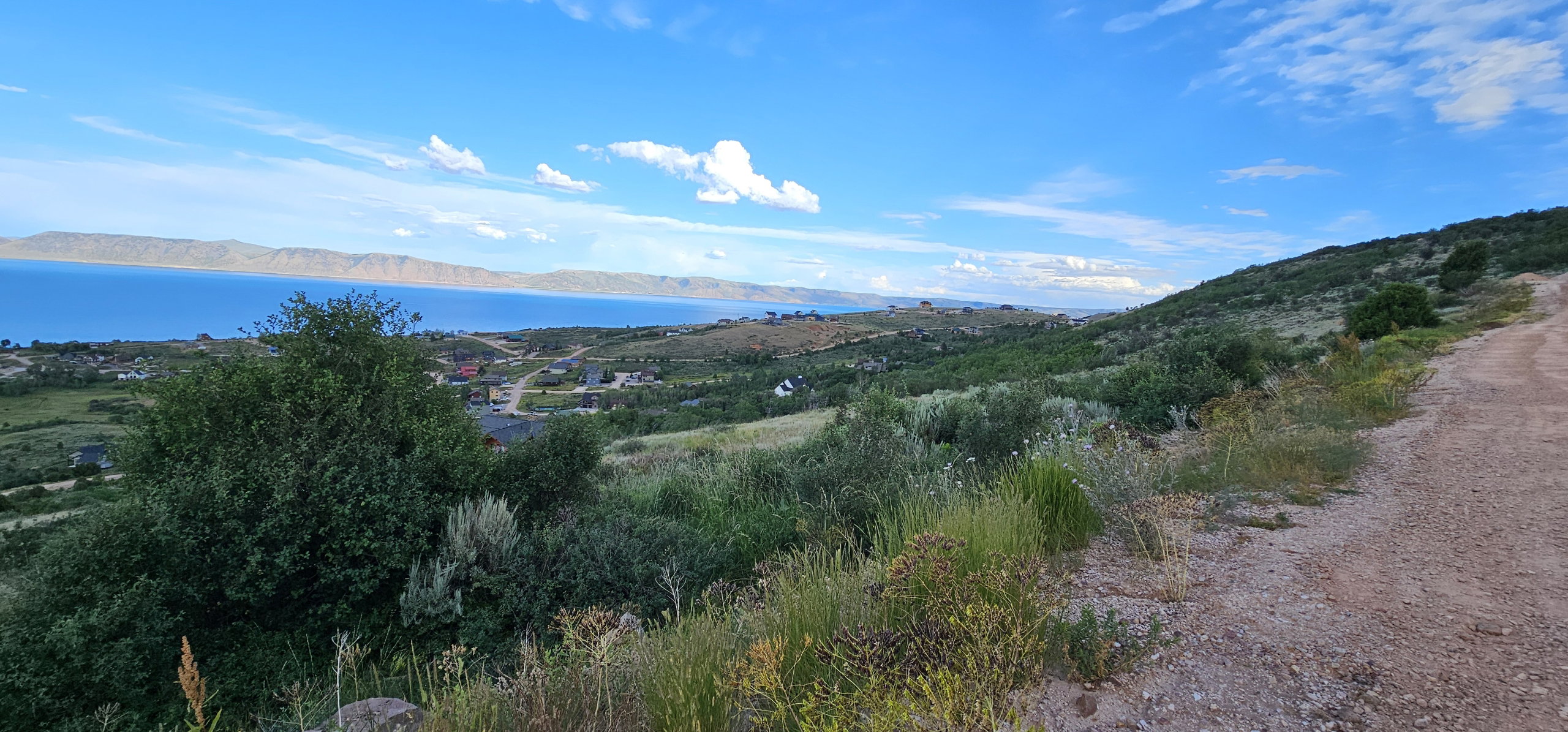 Expansive hillside landscape featuring distant water and mountain ranges