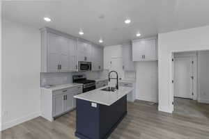 Kitchen featuring stainless steel appliances, a center island with sink, light stone counters, tasteful backsplash, and recessed lighting