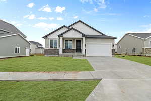 Craftsman-style home featuring stone siding, concrete driveway, a front lawn, a porch, and a garage
