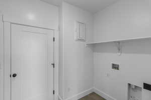 Laundry room with hookup for a washing machine, electric panel, and wood finished floors