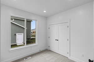 Unfurnished bedroom with light colored carpet, a closet, and recessed lighting