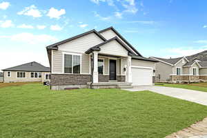 Craftsman inspired home featuring stone siding, a front yard, concrete driveway, and a garage