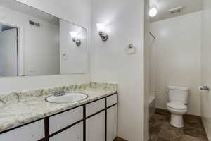 Bathroom with vanity, stone finish floors, and shower / bath combination