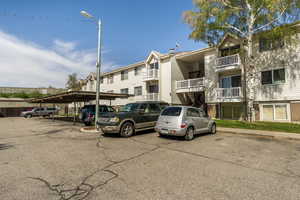View of apartment building / complex with covered and uncovered parking