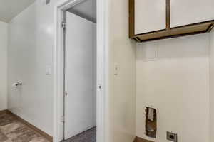 Laundry area with electric dryer hookup and cabinet space
