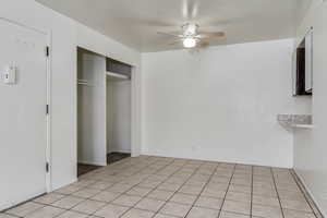 Unfurnished bedroom with a closet, a ceiling fan, and light tile patterned floors