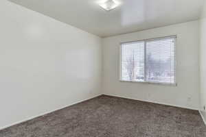 Empty room featuring dark carpet and baseboards