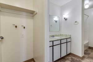 Bathroom featuring vanity, stone finish flooring, and  shower combination