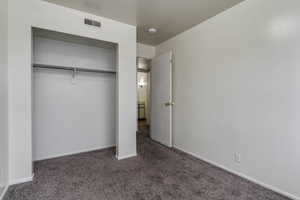 Unfurnished bedroom with dark carpet and a closet
