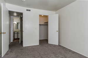 Unfurnished bedroom featuring carpet flooring and a walk in closet