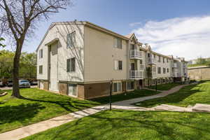 View of side of property with a yard, a balcony, and brick siding