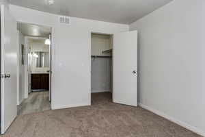 Unfurnished bedroom with a spacious closet and light colored carpet