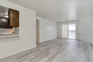 Unfurnished living room featuring light wood finished floors and baseboards