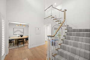 Stairway with wood finished floors, suspended lighting, and a high ceiling