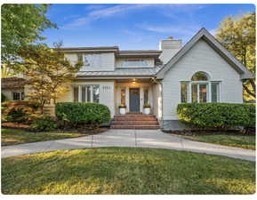 View of front of house featuring a front lawn, a standing seam roof, brick siding, and a chimney