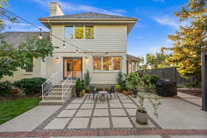 Back of property featuring a patio area, a chimney, brick siding, and outdoor dining space