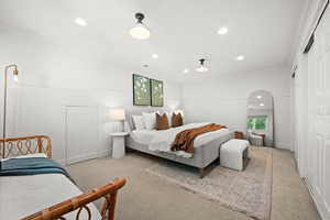 Bedroom featuring recessed lighting, crown molding, light carpet, arched walkways, and a closet