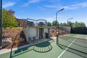 View of tennis court featuring a patio area