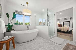 Ensuite bathroom featuring tile walls, a shower stall, a soaking tub, ornamental molding, and a wainscoted wall