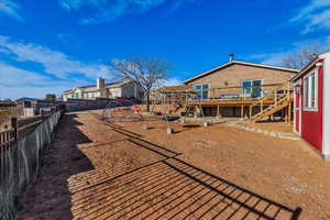 Rear view of house featuring a wooden deck, a playground, a fenced backyard, and a residential view