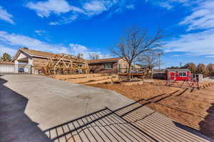 View of front of property with a shed, a gate, a patio, and concrete driveway