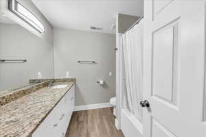 Full bathroom with vanity, light wood-style floors, and shower / bath combo with shower curtain