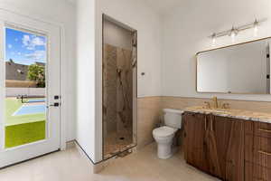 RV Garage Full Bathroom featuring vanity, a marble finish shower, tile walls, and wainscoting