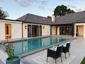 Rear view of property with a patio area, an outdoor pool, a chimney, and stucco siding