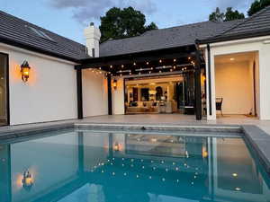 Rear view of property with an outdoor pool, a patio, a chimney, and stucco siding