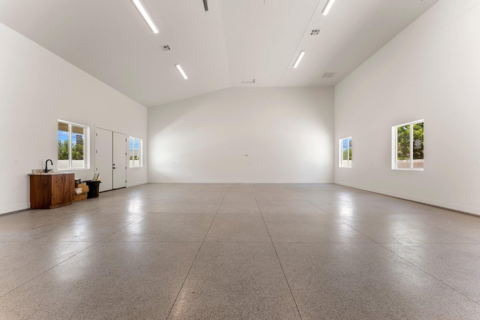 Spare room featuring vaulted ceiling and dark aggregate flooring