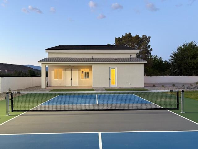Back of house at dusk with a sport court, a patio, and stucco siding