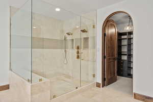 Full bathroom featuring a spacious closet, a shower stall, and recessed lighting
