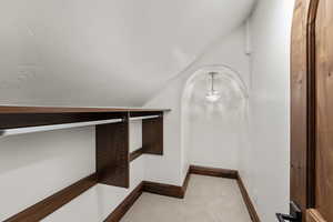 Walk in closet featuring vaulted ceiling, light carpet, and hanging lights
