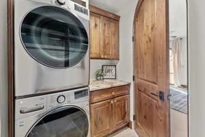 2nd Primary Owner Suite Laundry area with cabinet space and stacked washing machine and dryer